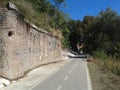 Bike lane to Rome with an ancient wall of stone with some graffiti and vegetation around, Italy.