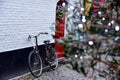 A bike leaned against a white brick wall building. Christmas lights on a nearby tree and a red door on the wall in Brugge, Belgium Royalty Free Stock Photo