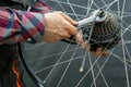 The bike mechanic installs a new cassette on the motor wheel. Repair of electric bicycles. Mechanic's hand and wrench