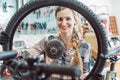 Bike mechanic woman looking through the wheel of bicycle