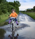 Bike in the park moving through puddle on rainy day. Boy on a bicycle at asphalt road in summer