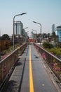 Bike path bridge in a city, surrounded by lots of plants and lamps, with buildings in the background Royalty Free Stock Photo