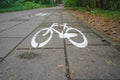 Bike path in the forest. Cycle path signed with white paint on the concrete. Royalty Free Stock Photo