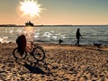 Bike  and people  silhouettes  walking  on the beach sand at  summer sunset on sea on skyline ,reflection of sunlight on wa of sun Royalty Free Stock Photo