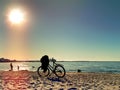 Bike  and people  silhouettes  walking  on the beach sand at  summer sunset on sea on skyline ,reflection of sunlight on wa of sun Royalty Free Stock Photo