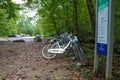 A bike rack filled with white bikes on a hiking trail filled with fallen autumn leaves surrounded by lush green trees