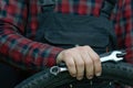 bike repair. Bike mechanic in the workshop. A mechanic holds tools and a bicycle wheel in his hand. Hands of the master and keys Royalty Free Stock Photo