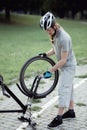 Bike repair. Young man repairing mountain bike in the park Royalty Free Stock Photo