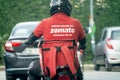 bike rider delivery boy with hot box branded with zomato the food tech delivery app in India and the iconic red uniform