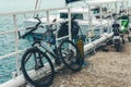 Bike stands on a pier against the background of a sailing yacht on azure sea water Royalty Free Stock Photo