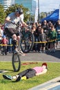 Bike stunts in the park. A rider does a wheelie over a volunteer
