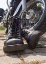 Biker boots with laces close-up standing near the wheel of a motorcycle chopper