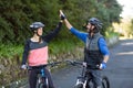 Biker couple giving high five while riding bicycle on the road Royalty Free Stock Photo