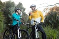 Biker couple standing with bicycle drinking water in forest