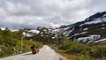 Biker drives alone on a beautiful highland, between snowy mountains in Norway during the summer Royalty Free Stock Photo