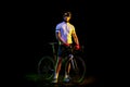 Full-length portrait of young male cyclist on bicycle in cycling shorts and protective helmet isolated on dark Royalty Free Stock Photo