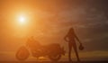 Biker girl and classic motorcycle at sunset