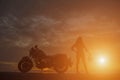 Biker girl and classic motorcycle at sunset