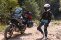 Biker girl in special motorcycle outfit, protection, knee pads and turtleneck. White helmet. Stands next to a long-distance Royalty Free Stock Photo