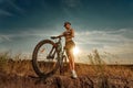 Biker-girl at the sunset with mountain bike. Woman with bicycle at sunrise on trail. Royalty Free Stock Photo