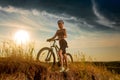 Biker-girl at the sunset with mountain bike. Woman with bicycle at sunrise on trail. Royalty Free Stock Photo