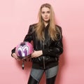 Biker girl wearing black leather jacket holding pink motorcycle helmet