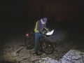 Biker lost path in night snowdrift. Man with mtb