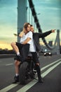 Biker man and girl stands on the road and looks into the distance. Love and romantic concept