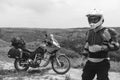 Biker man in a helmet and motorcycle equipment, jacket turtle, body armor. Close. In the background a touristic motorcycle. The