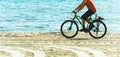 Biker man riding the titan mountain bike along sunny sandy beach