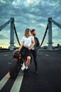 Biker man and girl stands on the road and looks into the distance. Love and romantic concept