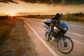 Biker and motorcycle on road at sunset Royalty Free Stock Photo