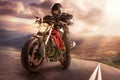 Biker on mountain highway, riding around a curve with a motion blur toned with a retro vintage instagram filter app or Royalty Free Stock Photo