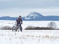 Biker is pushing bike in deep snow alone. Mtb rider lost the road