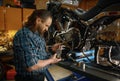 Biker repairman looking at spare part in his and while working in garage