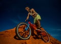 Biker rides on the high mountains of red sand dunes .