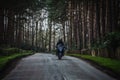 Biker rides a motorcycle on a road in the forest Royalty Free Stock Photo