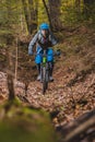 Biker riding downhill with a modern electric bicycle or mountain bike in autumn or winter setting in a forest. Modern e-cyclist in Royalty Free Stock Photo