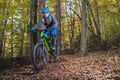 Biker riding downhill with a modern electric bicycle or mountain bike in autumn or winter setting in a forest. Modern e-cyclist in Royalty Free Stock Photo