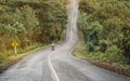 Biker is riding a motorcycle on the road to the top of the hill. Royalty Free Stock Photo