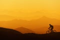 Biker Riding On Mountain Silhouettes Background
