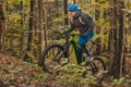 Biker riding uphill with a modern electric bicycle or mountain bike in autumn or winter setting in a forest. Modern e-cyclist in Royalty Free Stock Photo