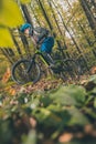 Biker riding uphill with a modern electric bicycle or mountain bike in autumn or winter setting in a forest. Modern e-cyclist in Royalty Free Stock Photo