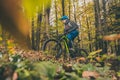 Biker riding uphill with a modern electric bicycle or mountain bike in autumn or winter setting in a forest. Modern e-cyclist in Royalty Free Stock Photo