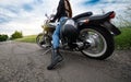 Biker sits on a motorcycle standing on a countryside cracked asphalt road