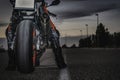 Biker sitting on black sports motorcycle on asphalt road dusk under cloudy sky. copy space