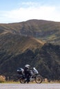 Biker is sitting on his adventure motorcycle, the top mountain in background, enduro, beautiful view, danger road in mountains,