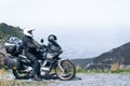 Biker is sitting on his adventure motorcycle, the top mountain in background, enduro, off road, beautiful view, danger road in