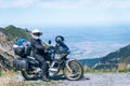 Biker is sitting on his adventure motorcycle, the top mountain in background, enduro, off road, beautiful view, danger road in