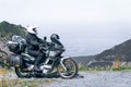 Biker is sitting on his adventure motorcycle, the top mountain in background, enduro, off road, beautiful view, danger road in